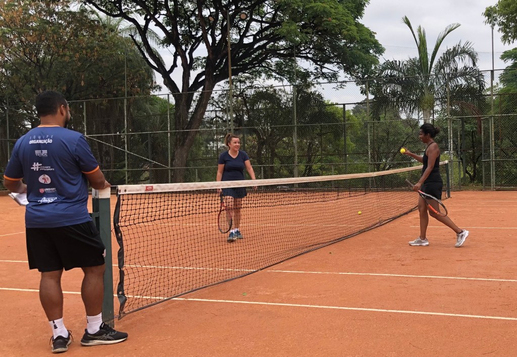 #ParaTodosVerem: Duas mulheres próximas da rede de uma quadra de tênis indo conversar com o arbitro do jogo.