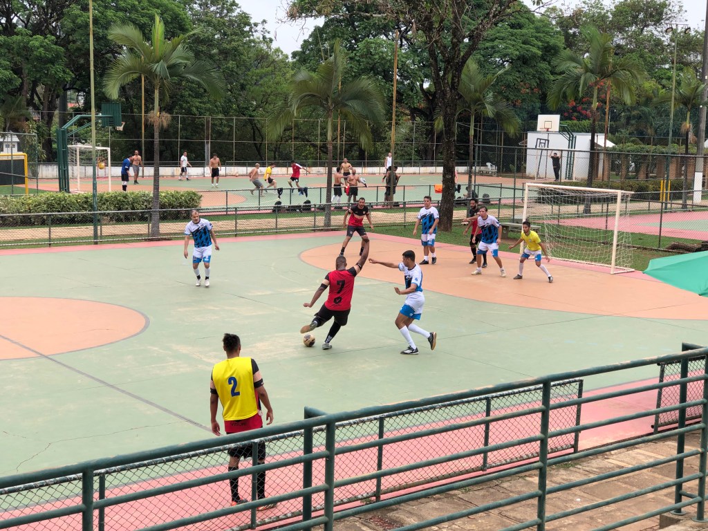 #ParaTodosVerem: Homens jogando futsal em quadra aberta com foco em um homem negro chutando para o gol.