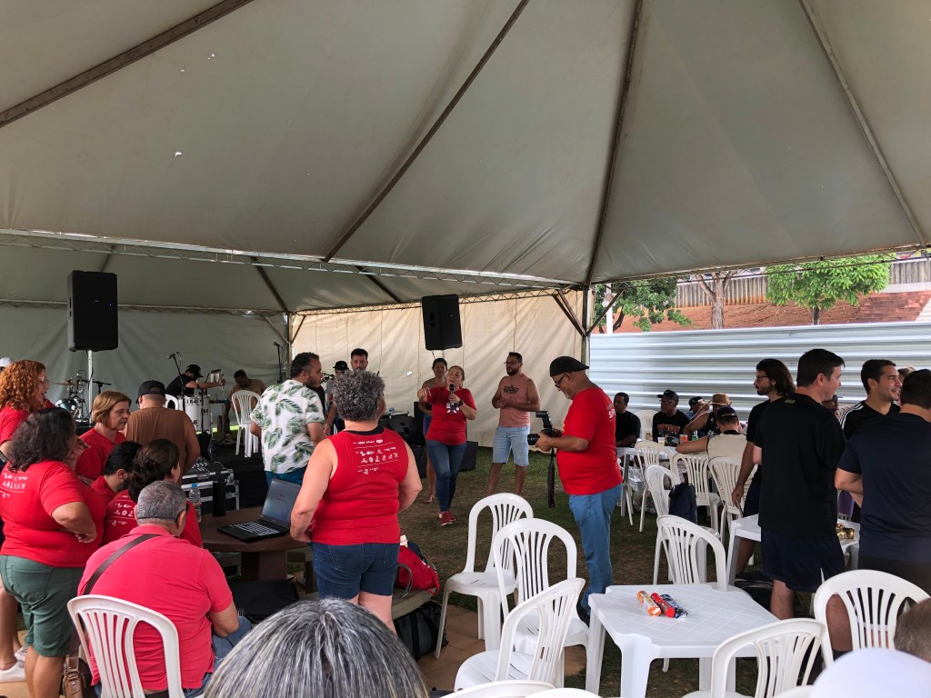 #ParaTodosVerem: Um aglomerado de pessoas em baixo de uma tenda esperando por um sorteio.